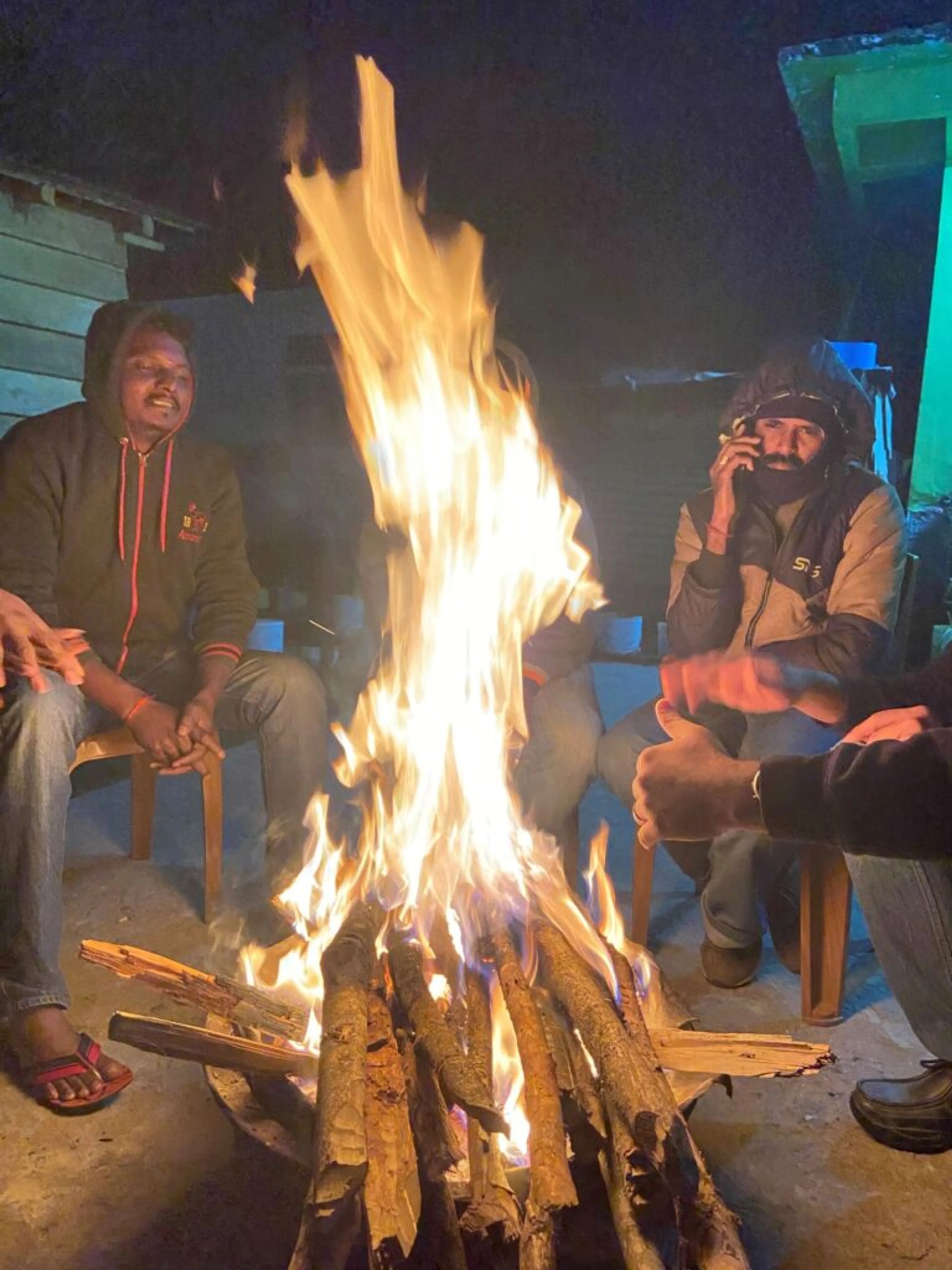 The members of the expedition warm up around a campfire